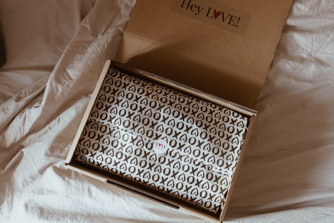 En öppen fraktkartong med ett personligt meddelande 'Hey LOVE!' på locket, vilket exemplifierar en personlig unboxing-upplevelse.